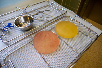 2 explanted silicone breast implants lie in an instrument basket