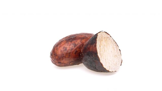 One whole and one half cut kola nut seeds rotating. Isolated on white background.