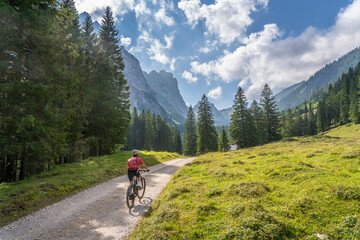 Fototapeta na wymiar beautiful active senior woman with electric mountainbike in the spectacular Mountains of Raintal Valley, a side valley of Lechtal, Tyrol, Austria