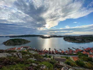 Fototapeta na wymiar Small Swedish Houses at the coastline of Fjällbacka in Sweden with the sun and clouds in the background - Drone Perspective Architecture Photography 