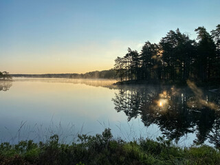 Obraz na płótnie Canvas Sunrise over a lake in Sweden with water reflections an a clear blue sky - Landscape Photography