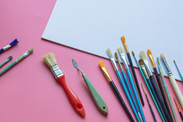 Paintbrushes and white canvas on pink paper background. Education, school and art concept. Free space for text or image