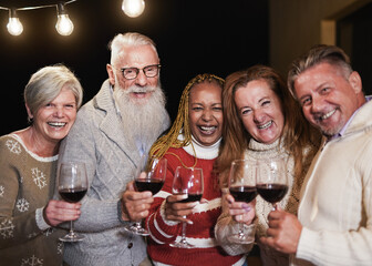 Senior multiracial people smiling on camera while celebrating christmas eve together