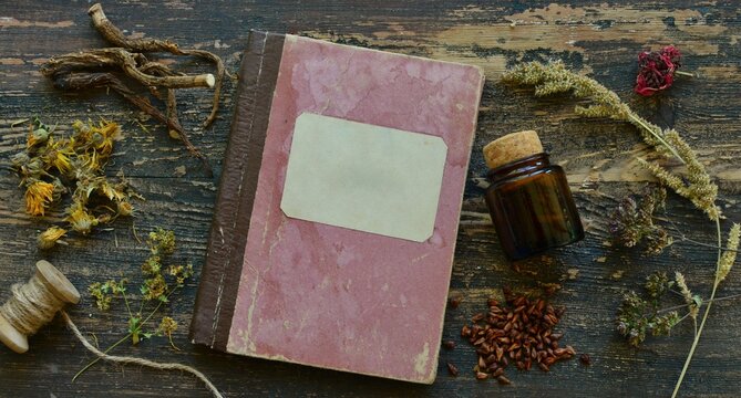 Old book and  medical herbs, roots and bottle with tincture on wooden background