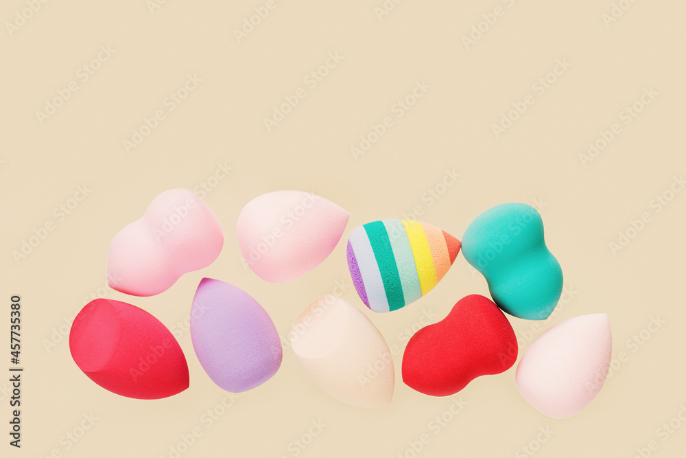 Wall mural Color cosmetic beauty blender sponges on nude colored background Colored sponges different shape.