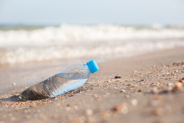 Fototapeta na wymiar Plastic bottle with water on the background of a sandy beach on a sunny day