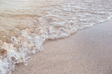 Soft transparent wave of the sea on a sandy beach