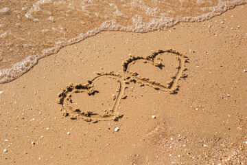 Two hearts drawn on a sandy beach. Top view, flat lay