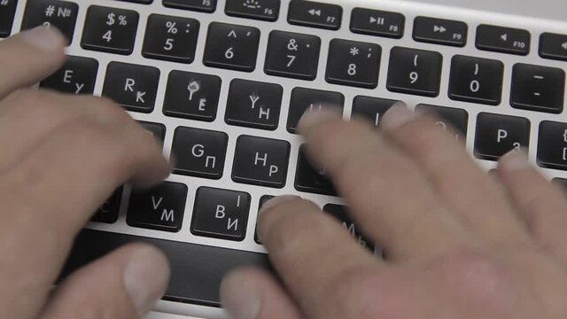 Computer work: Hands are typing on a macbook keyboard. Close-up
