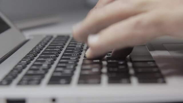 Computer work: Hands are typing on a macbook keyboard. Close-up