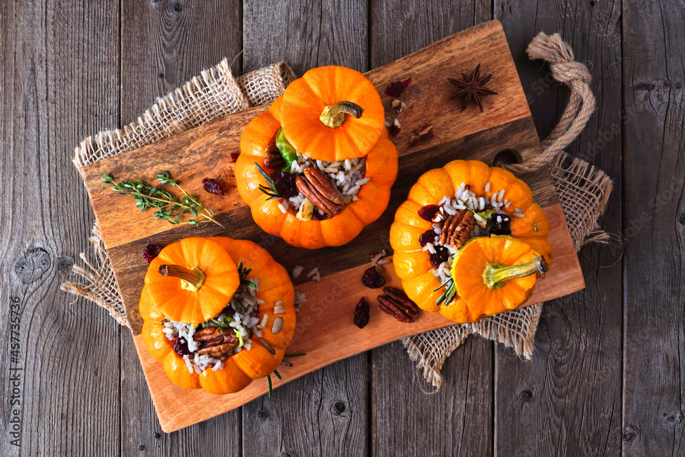 Wall mural Stuffed mini pumpkins with rice, cranberries, cabbage and nuts. Autumn food concept. Overhead view on platter on a rustic wood background. - Wall murals