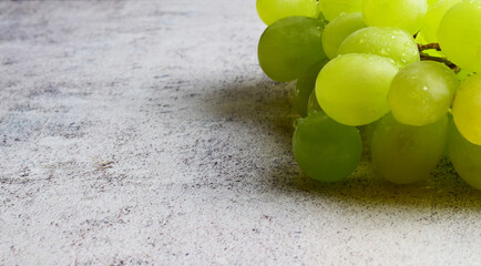 Part of bunch of white grapes on stone background and copy space.