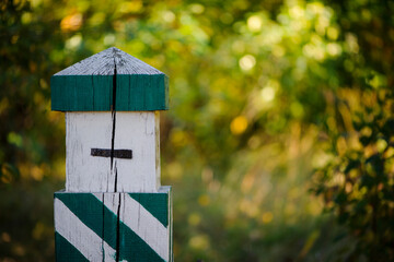 Quarterly pillar in the forest. A wooden pillar for a landmark in the forest. Forestry post. wood post with green stripes, blurred natural background. space for text