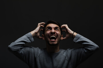 Portrait of young man screaming. Looking up in anger and making angry hand gestures