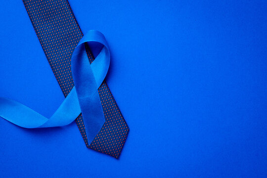 Cancer awareness blue. Blue ribbon, fashion tie isolated on deep blue background. Awareness prostate cancer of men health in November. November and International Mens Day.