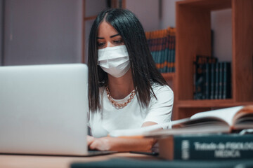 Mujer adolescente de cabello oscuro tecleando en el computador portatil los informes y trabajos de la universidad
