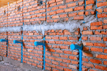 Water supply pipe layout work. Chrome pipes and fittings on brick wall background. Piping with many fittings. Pipes for water supply systems. Concept designing layout of utilities. Fragment of a room.