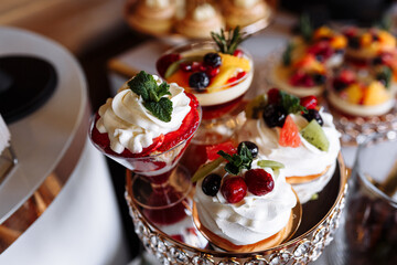 luxury wedding catering, table with modern desserts, cupcakes, sweets with fruits. delicious candy bar at expensive wedding reception. party holiday celebration. selective focus
