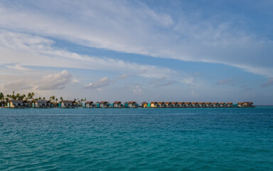 Island in ocean, overwater villas at the sunrise. Crossroads Maldives, july 2021