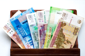 Brown leather wallet with Russian banknotes in denominations of 100, 200, 500, 1000, 2000 and 5000 rubles, highlighted on a white background. the concept of finance, investment, savings and cash.