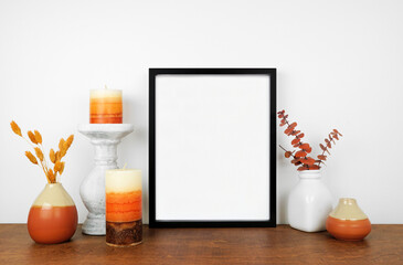 Mock up black frame with fall branches and decor on a wood shelf. Autumn concept. Portrait frame...