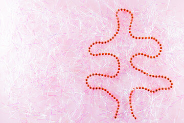 Symbol Christmas and Happy New Year figure christmas tree with red beads on tinsel. Christmas beads on pink tinsel. Holiday concept. Top view