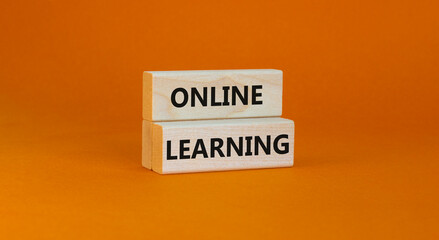 Online learning symbol. Concept words 'Online learning' on wooden blocks on a beautiful orange background. Business, educational and online learning concept, copy space.