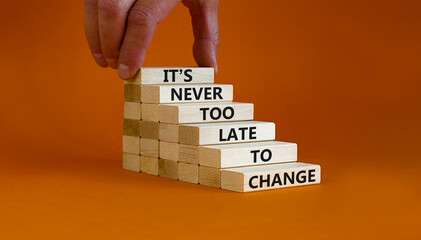 Change symbol. Wooden blocks with words 'It is never too late to change'. Businessman hand. Beautiful orange background, copy space. Business and It is never too late to change concept.