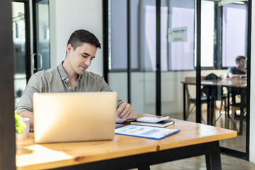 Young businessman sitting in the office at his company, he is checking the correctness of company financial documents, young businessman running a startup business is constantly profitable.