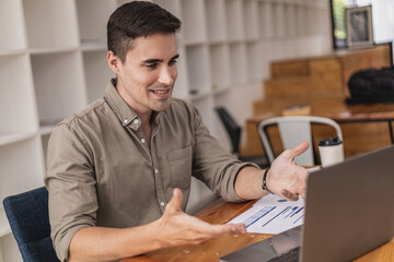 Fototapeta premium Handsome man talking to people in a video call on the laptop. Businessmen use video conferencing to communicate in organizations around the world. Teleconferencing is used in business and education.