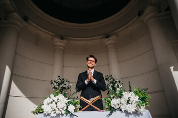 Portrait of young cheerful Caucasian marriage officiant during wedding ceremony