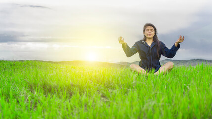 Woman in the field sitting meditating, woman doing yoga in the cool field