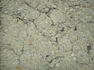 Texture of gray cracked clay rock. Clay walls with cracks.