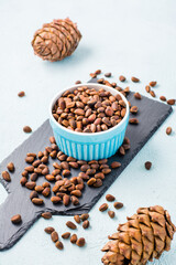 A bowl of unpeeled pine nuts and pine cones on a slate board. Detox and cure for insomnia. Healthy vitamin nutrition. Vertical view