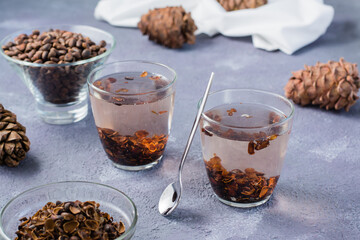Infusion of pine nut shells in glasses and pine nuts on the table. Alternative medicine.