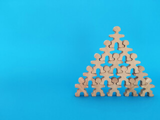 Teamwork and cooperation concept, wooden people standing shoulder to shoulder forming a pyramid