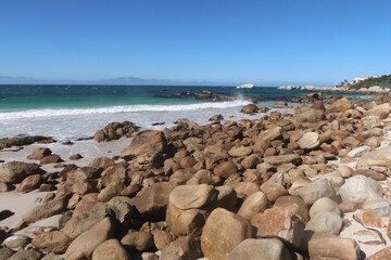 Scenic turquoise Indian ocean water along sandy beach with large granite boulders near Simons's town, on the Cape Peninsula, Cape Town, South africa