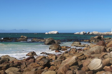Scenic turquoise Indian ocean water along sandy beach with large granite boulders near Simons's town, on the Cape Peninsula, Cape Town, South africa