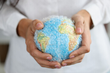 Woman holds plastic covered globe showing environmental problems