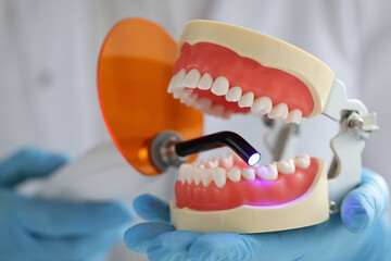 Doctor holds jaw and dental UV lamp to fill dental jaw