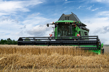 Fototapeta premium Getreideernte - Moderner Mähdrescher bei trockenem Erntewetter auf dem Feld im Einsatz.