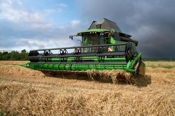 Fototapeta premium Getreideernte - Moderner Mähdrescher bei trockenem Erntewetter auf dem Feld im Einsatz.