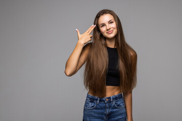 Head shot studio portrait on grey background, gloomy woman in glasses looking at camera puts fingers gun aimed to head killing herself gesture, symbol of exhaustion big problems unhappy woman concept