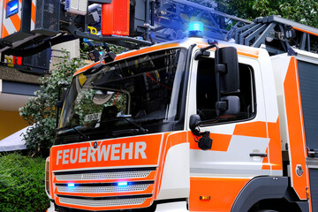 red fire truck in the courtyard of a multi-storey building arrives on call, emergency 112 concept for a fire in Germany, flashing lights