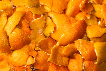 Close-up blurred background of dried orange and tangerine skins. Lots of small pieces of dried orange peel, stacked together. Bright orange background, backdrop. Good New Year spirit. No focus