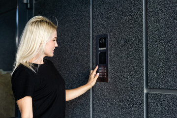woman dialing an intercom to enter a building