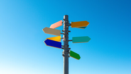 Guidepost with bright colored arrows against blue sky