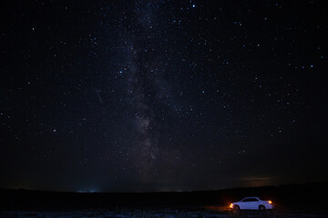 car and the milky way in the field at night