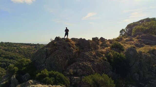A beautiful high angle drone footage of a man in a thick forest in Sardinia
