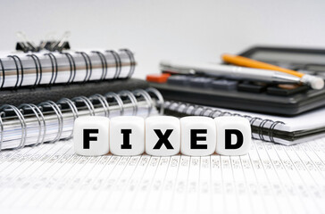 On the table, among office objects, cubes with the inscription - FIXED